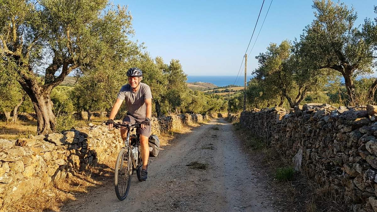 Person cycling a bike down a quiet rural lane toward the coast on the Costa Vicentina