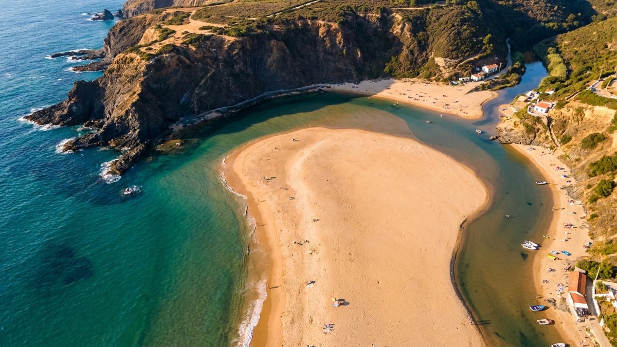 Aerial view of Praia de Odeceixe with the river Seixe on one side and Atlantic waves on the other